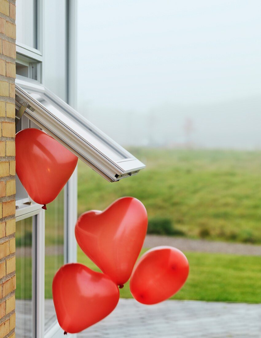 Heart-shaped balloons floating out of window
