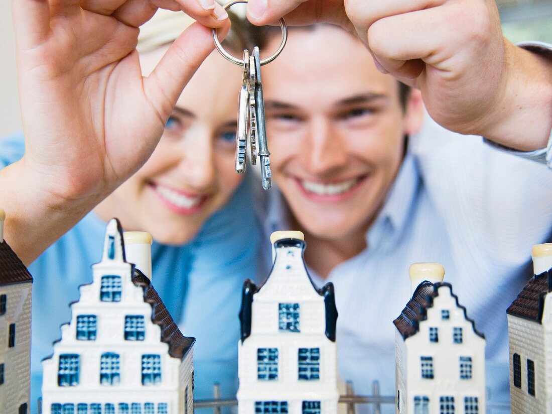 Couple holding bunch of keys above model houses