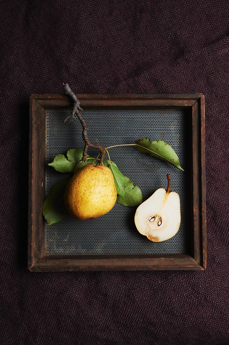 Whole and Half of a Kieffer Pear in a Shallow Wooden Box