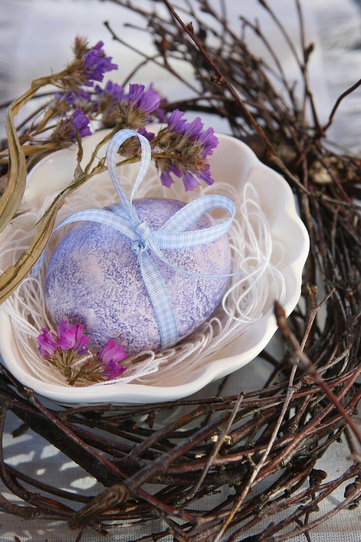 Light blue Easter egg with bow in nest