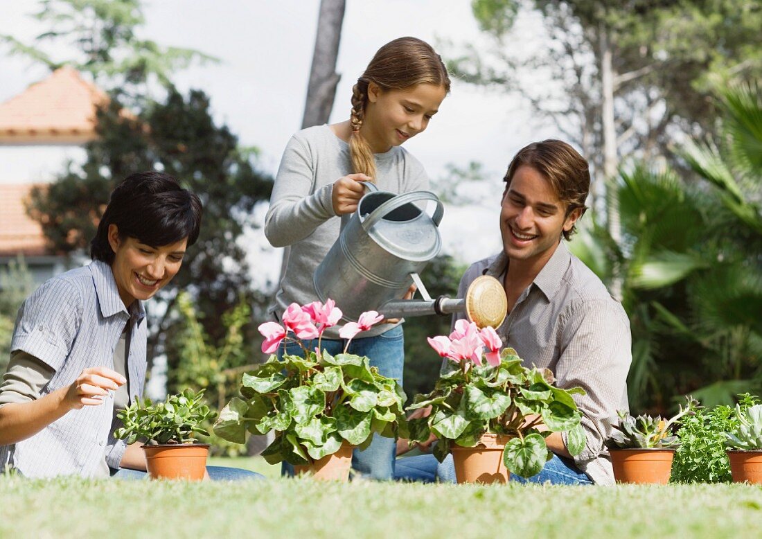 Familie im Garten gießen Blumen im Topf