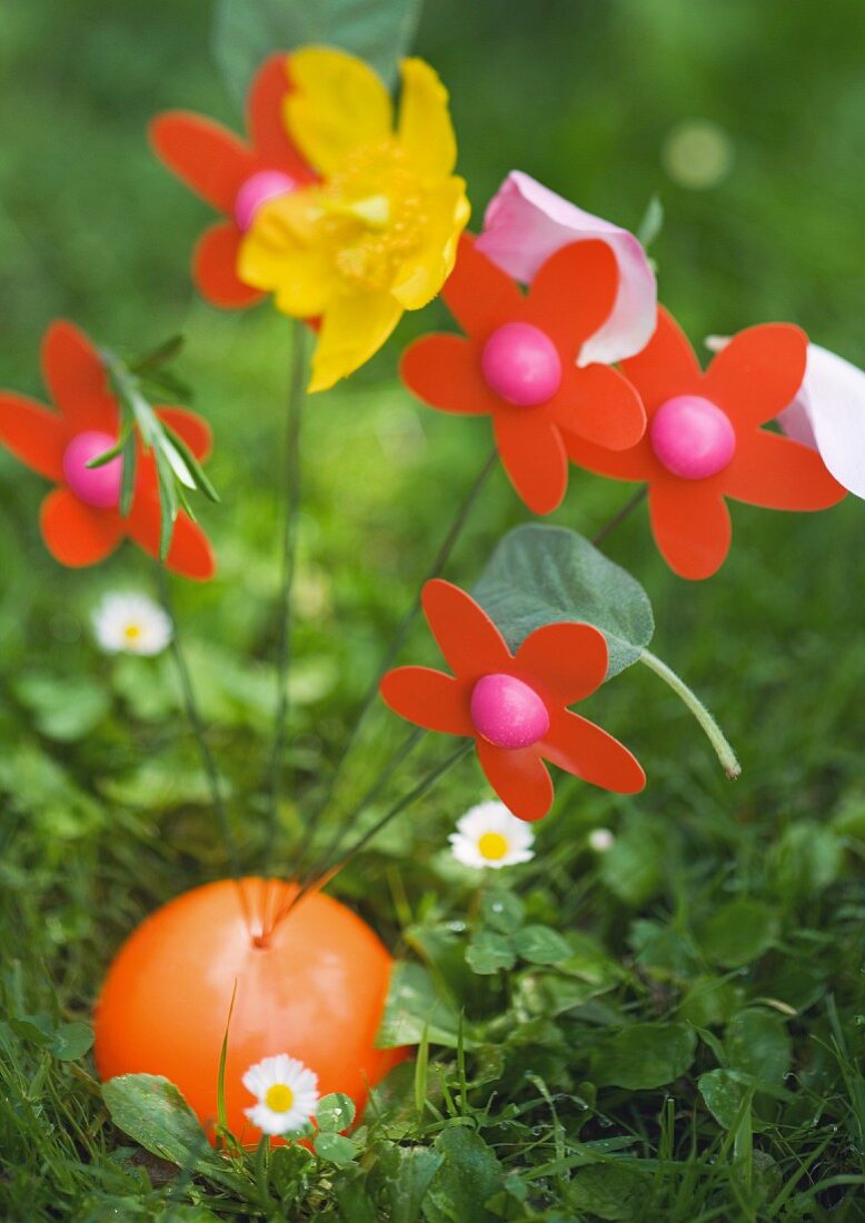 Künstliches Blumengesteck auf der Wiese mit Blumenblüten dekoriert