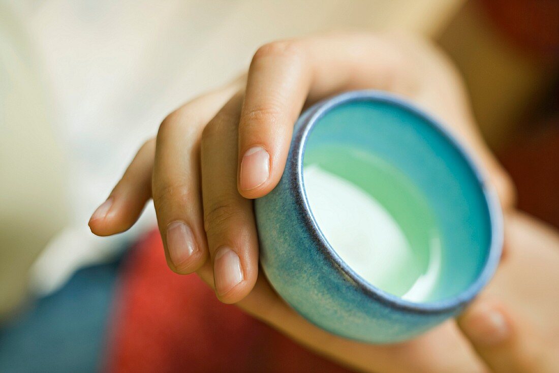 Hands holding cup of green tea