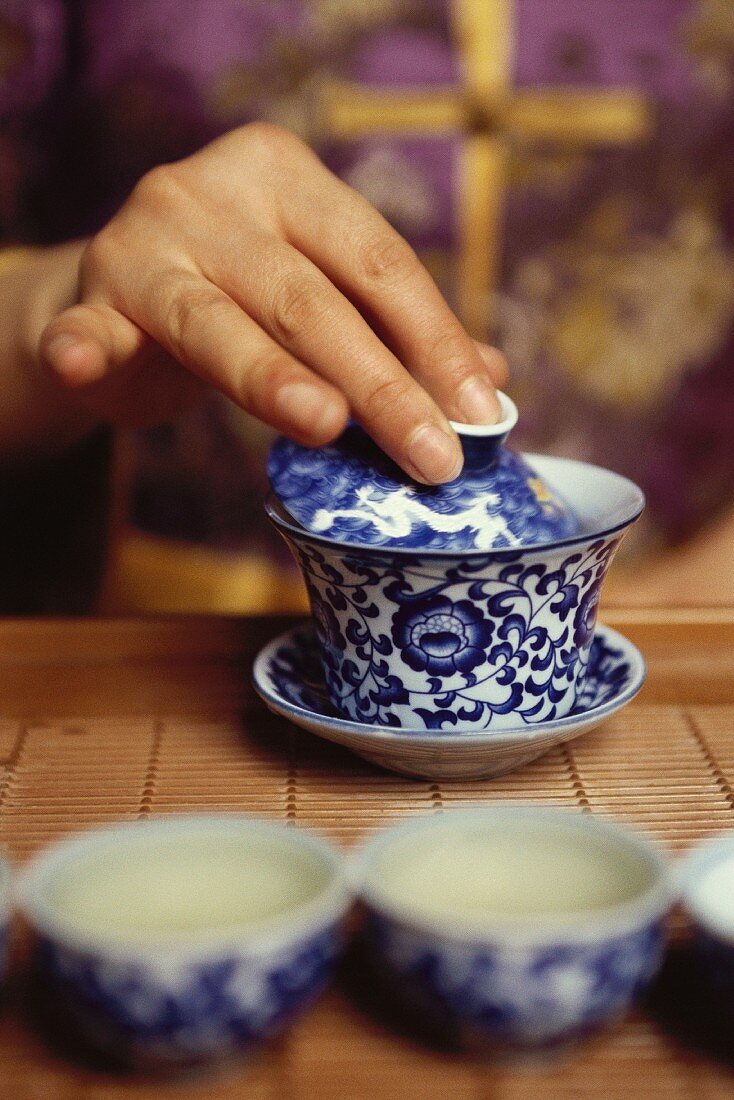 Hand placing lid on tea cup
