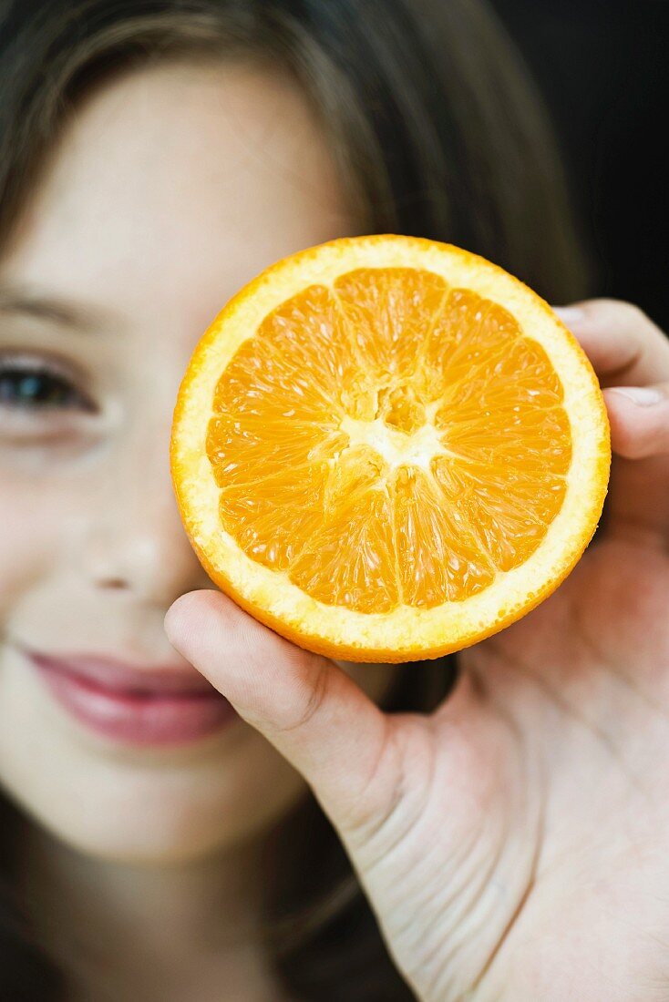 Girl holding up orange slice