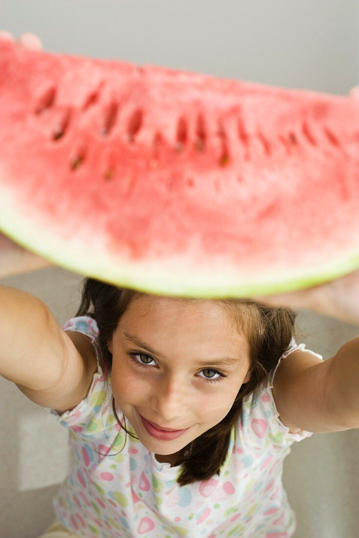 Mädchen hebt eine Wassermelonenspalte hoch