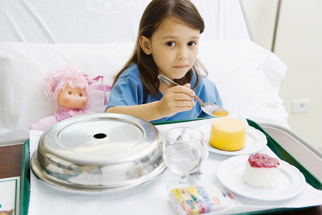 Girl eating meal in hospital bed