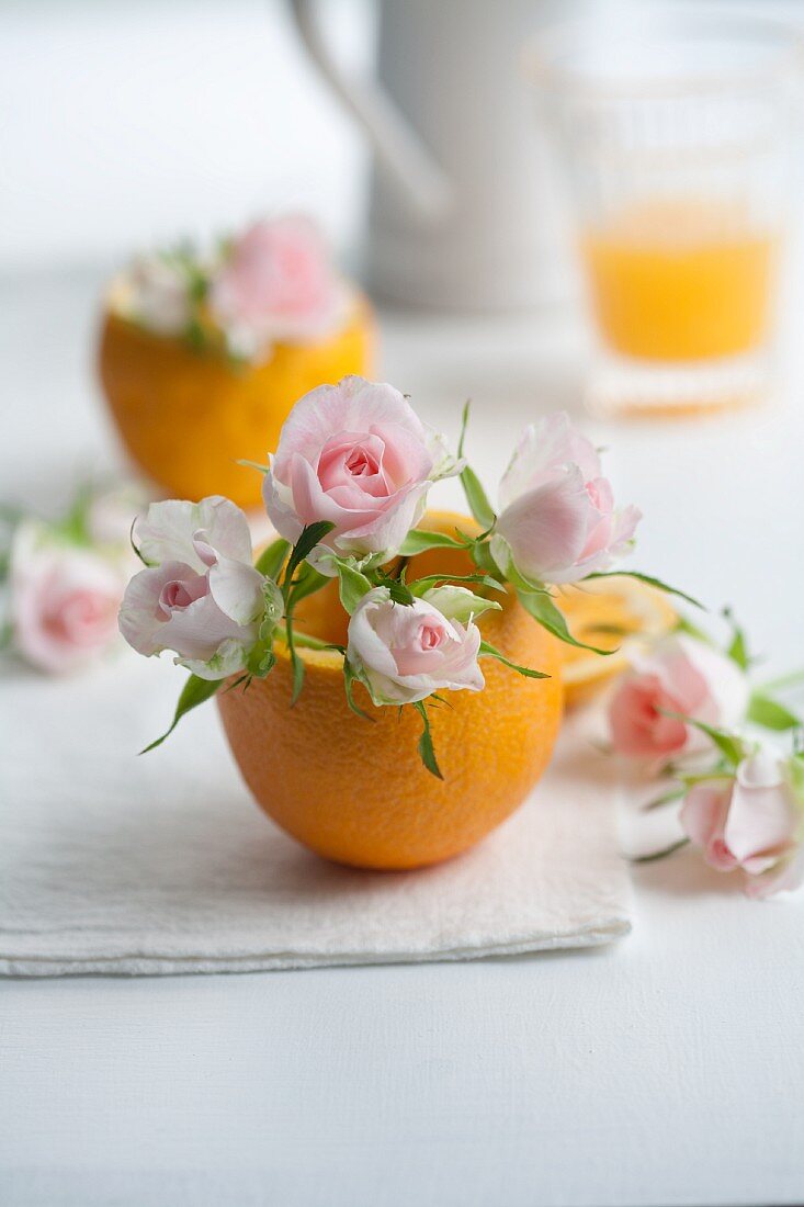 Orangenhälfte mit rosa Rosen
