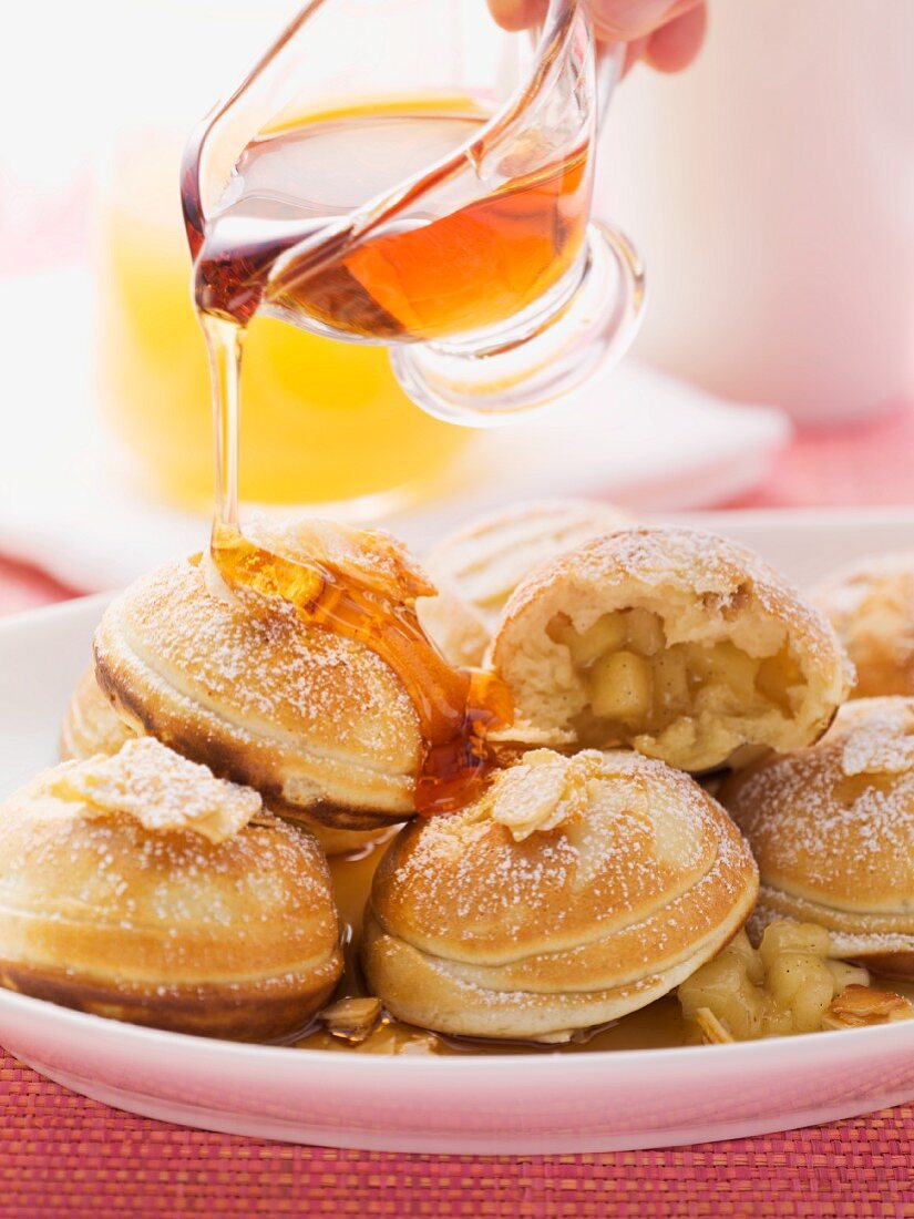 Aebleskiver (apple-filled Danish pastries) being drizzled with maple syrup