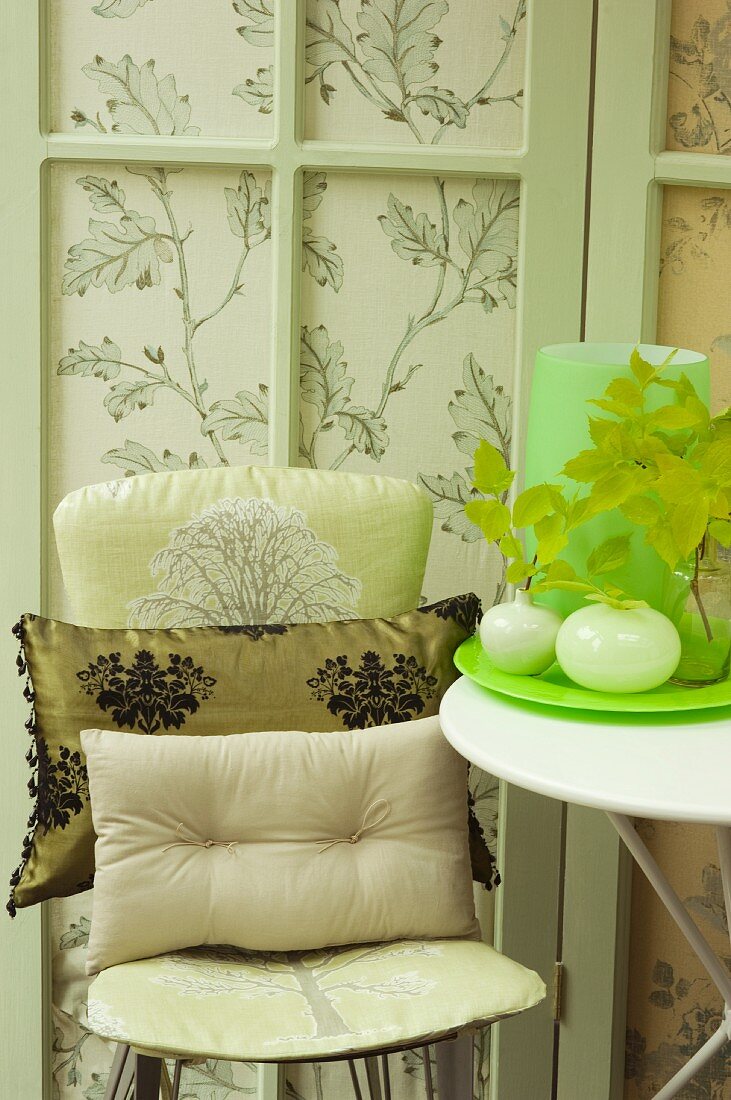 Cushions on chair against patterned fabric screen