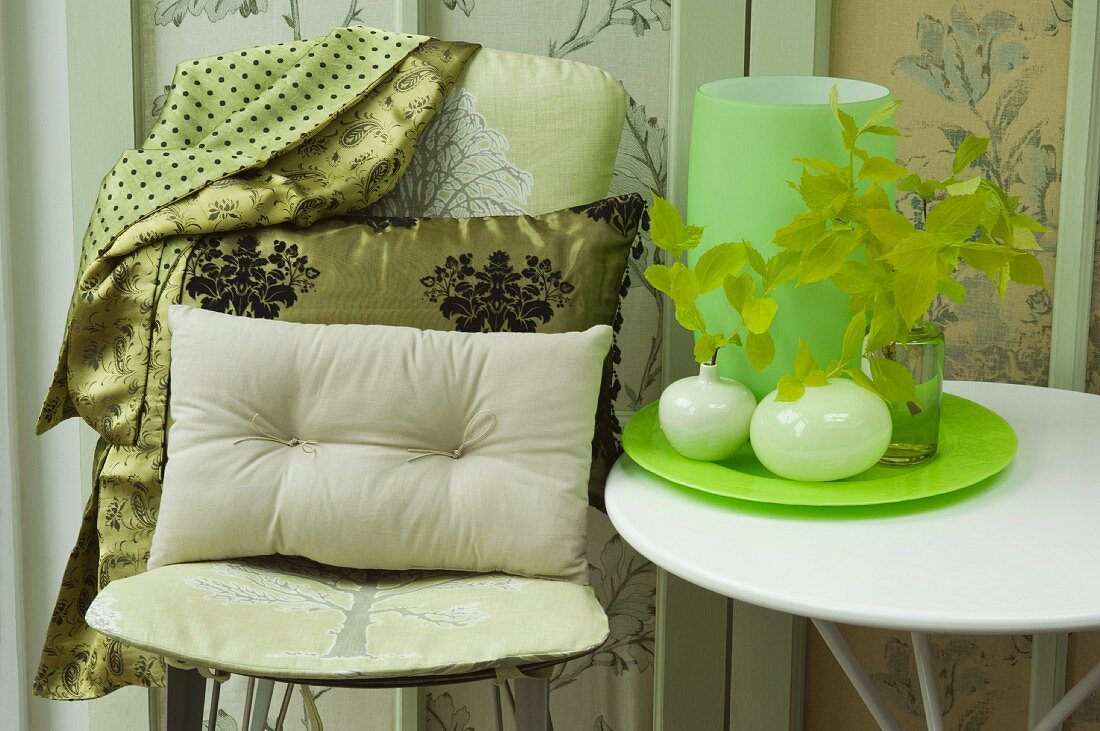 Stuhl mit Kissen und Beistelltisch mit Vasen auf Tablett