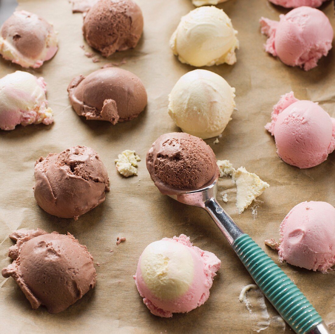 Various ice cream scoops on baking paper with an ice cream scoop