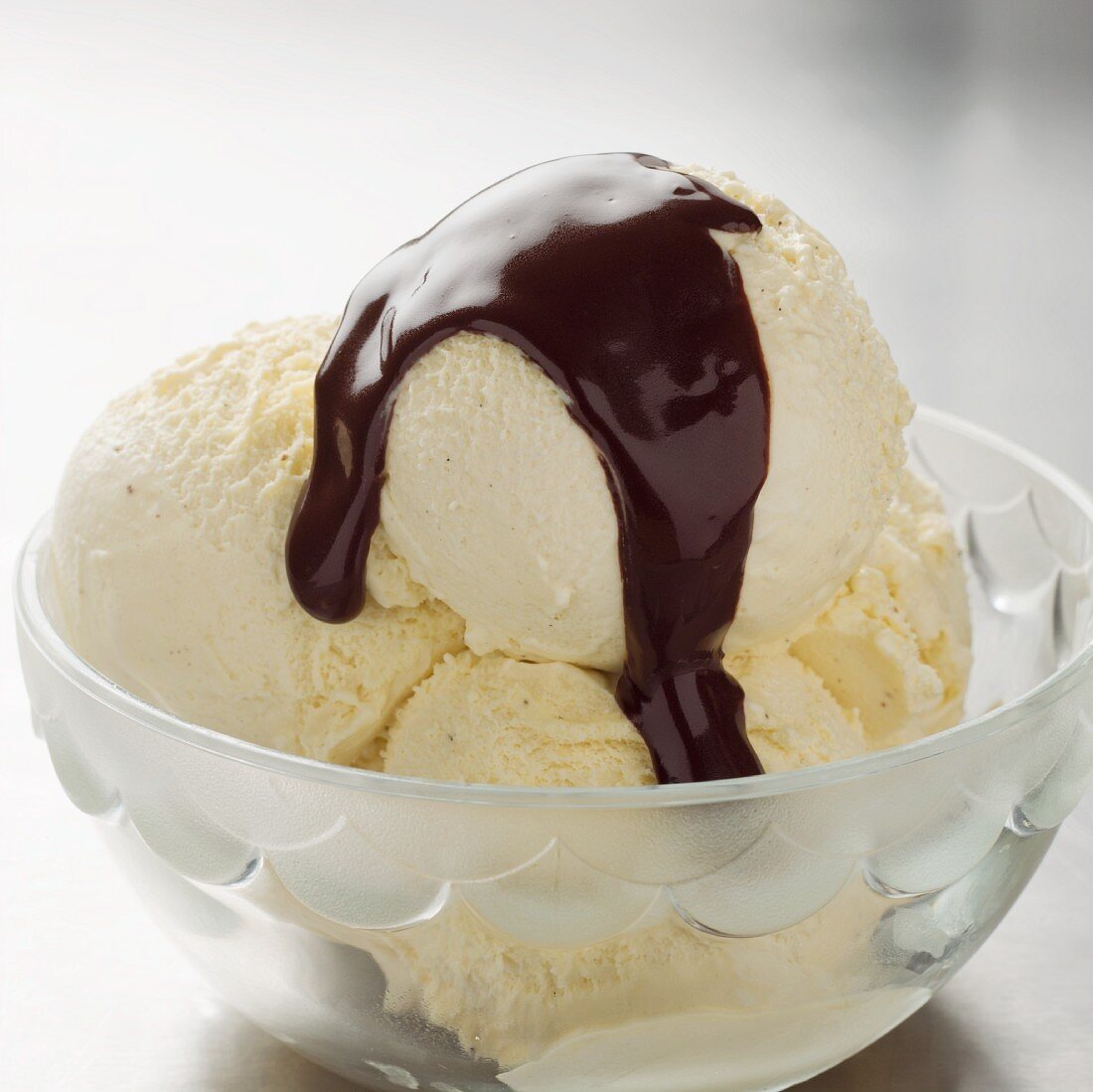 Vanilla ice cream with chocolate sauce in a glass bowl