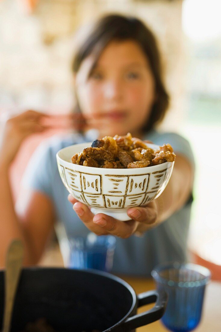 A girl holding a bowl of Oriental food