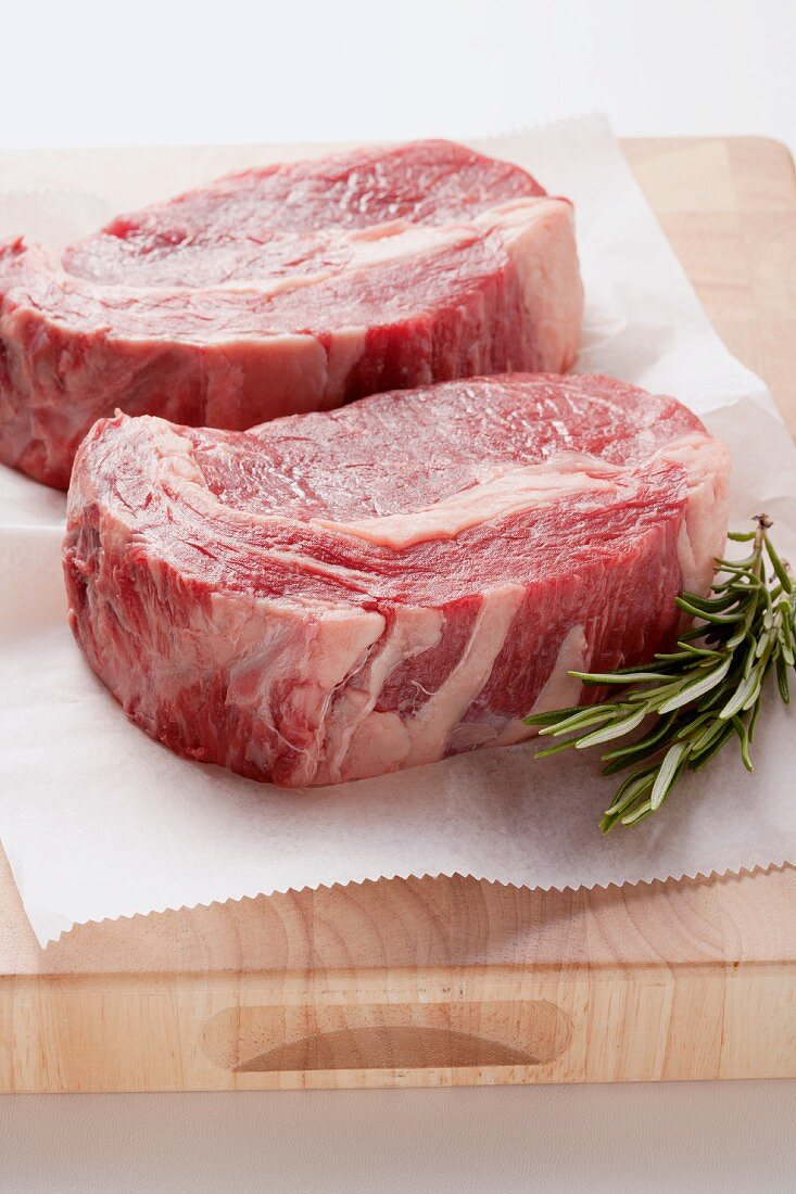 Beef steaks with paper on a wooden board