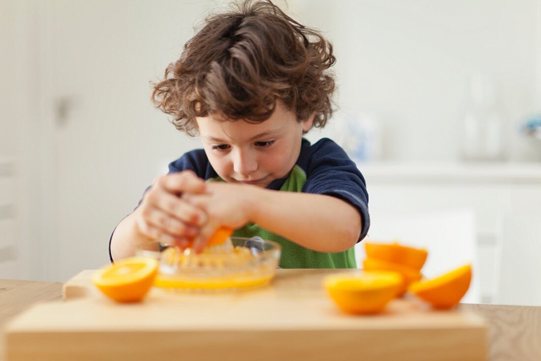 Kleiner Junge presst Orangensaft aus