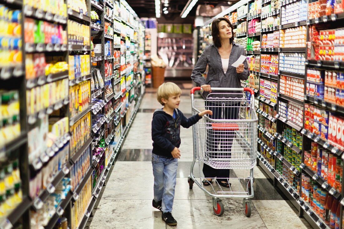 Frau mit Sohn kauft im Supermarkt ein