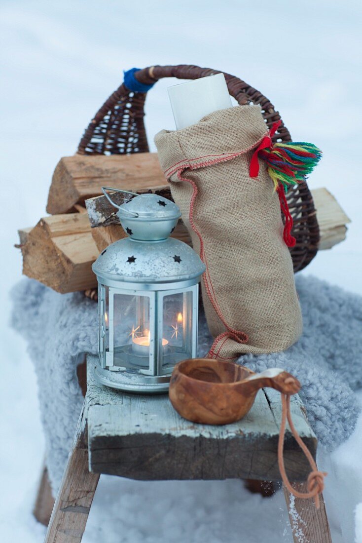 Holzkorb, Laterne und Holzbecher im Schnee