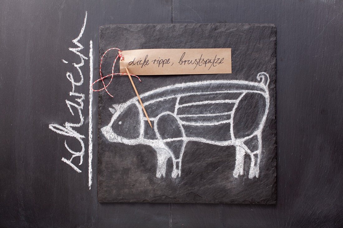 Gezeichnetes Schwein und Etikett mit Bezeichnung auf einer Schiefertafel