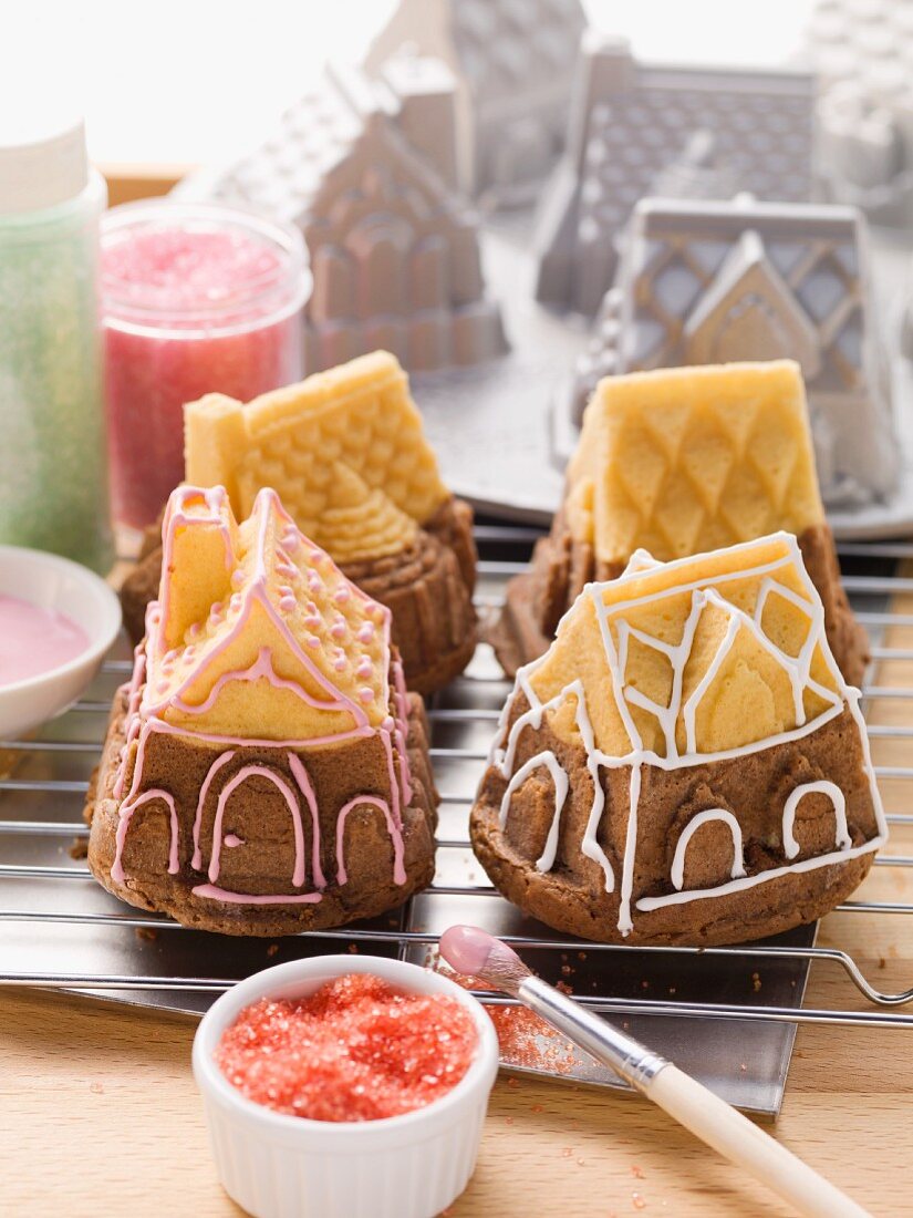 Small house-shaped cakes with the baking tins in the background
