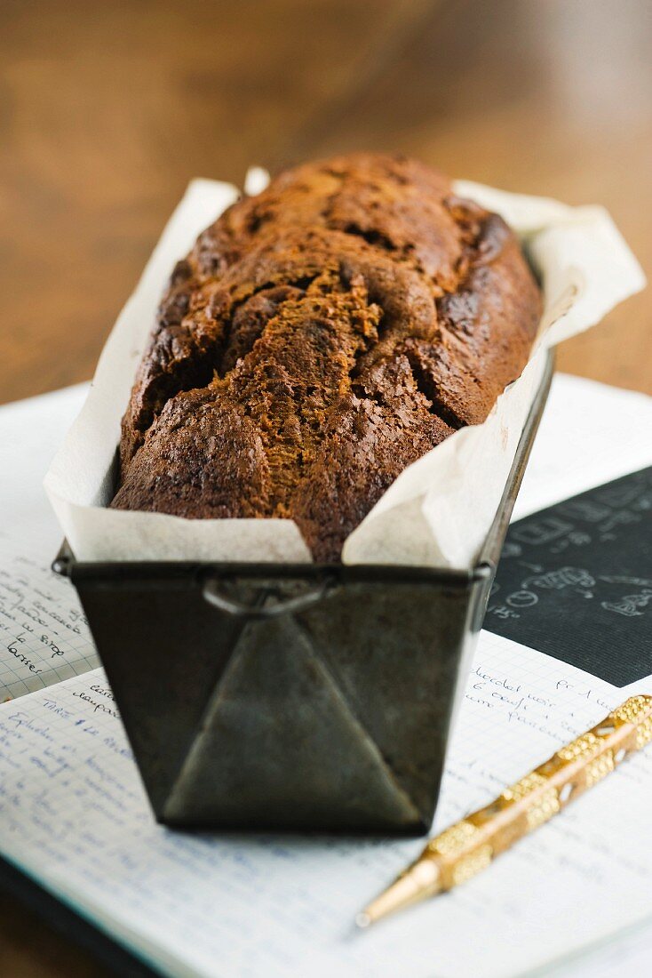 A loaf cake in a baking tin on a book