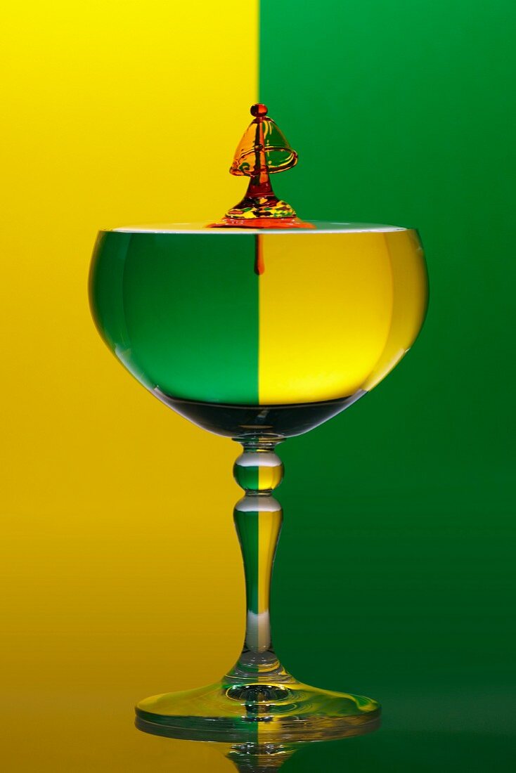 Weinglas mit Wassertropfen und grün gelben Hintergrund