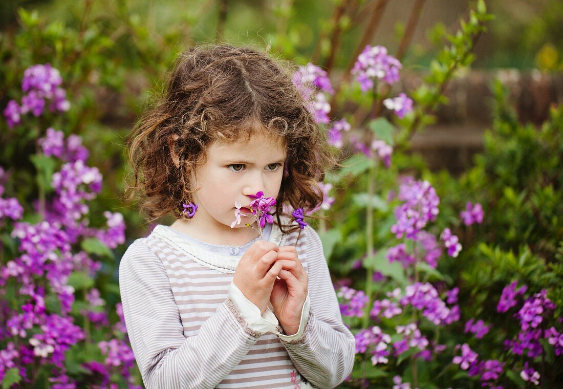 A little girl smelling flowers in a garden