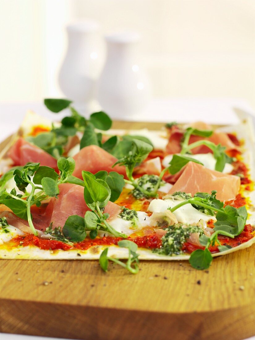 Unleavened bread topped with pesto, ham and cress