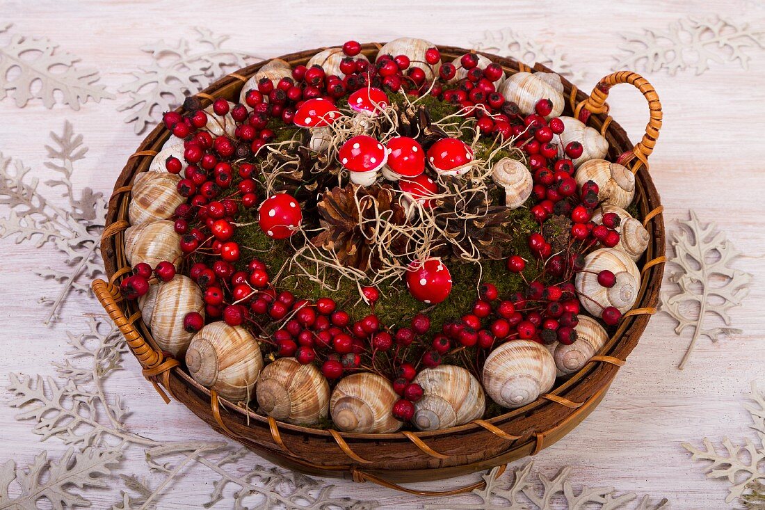 Korb mit Schneckenhäusern, Beeren und Fliegenpilzen