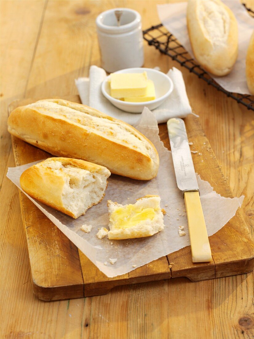 A mini baguette and butter on a wooden board