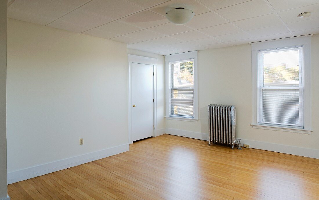 Empty room in apartment with hardwood floor and heater