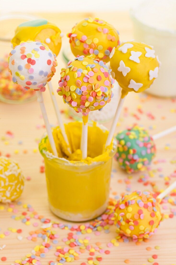 Various cake pops in a glass of yellow icing