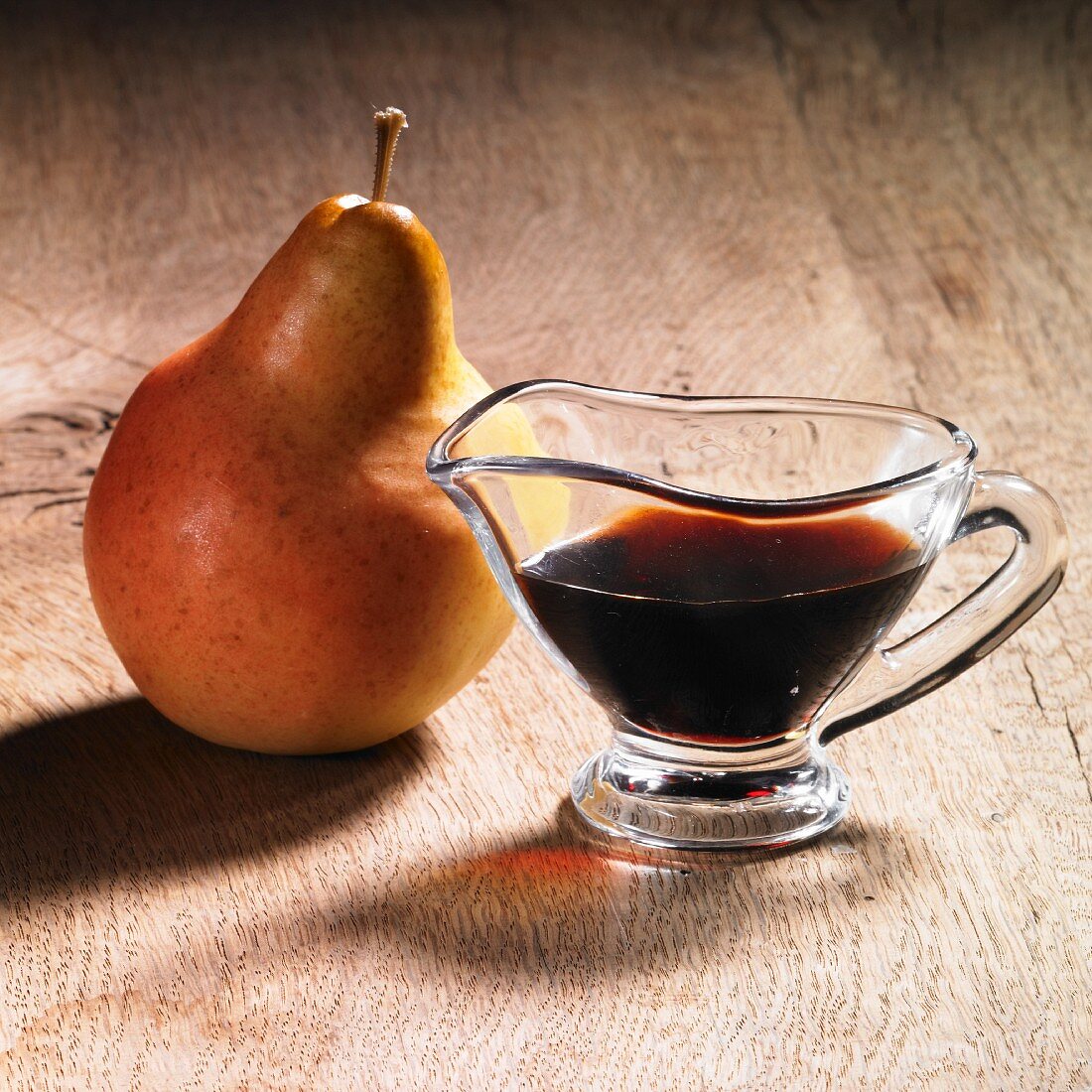 Apple and pear syrup in a gravy boat and a pear