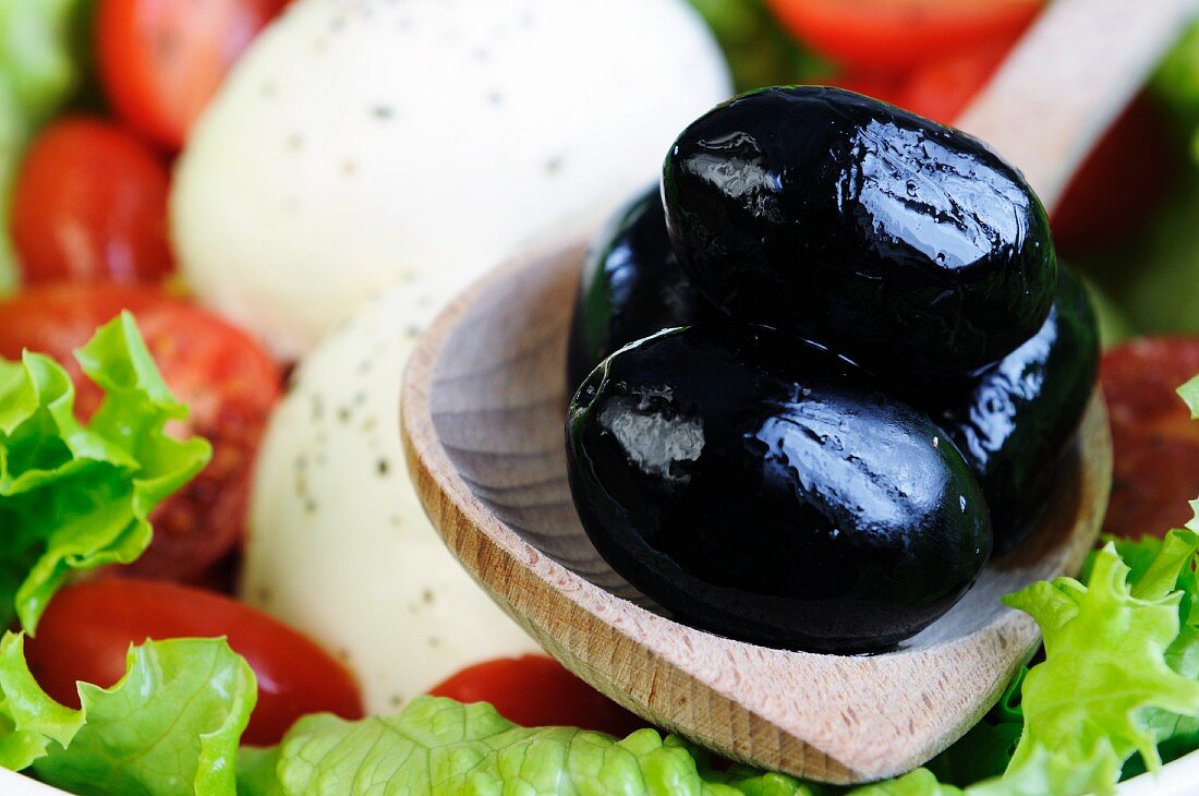 Mozzarella mit Tomaten, grünen Salatblättern und Oliven