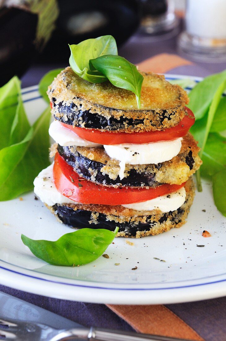 A tower of fried aubergine slices, tomato and mozzarella