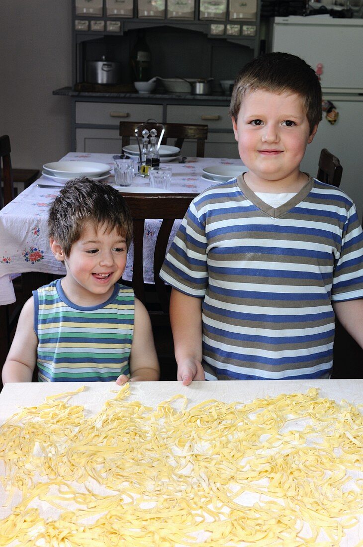 Zwei kleine Jungen vor Tisch mit frischgemachter roher Pasta