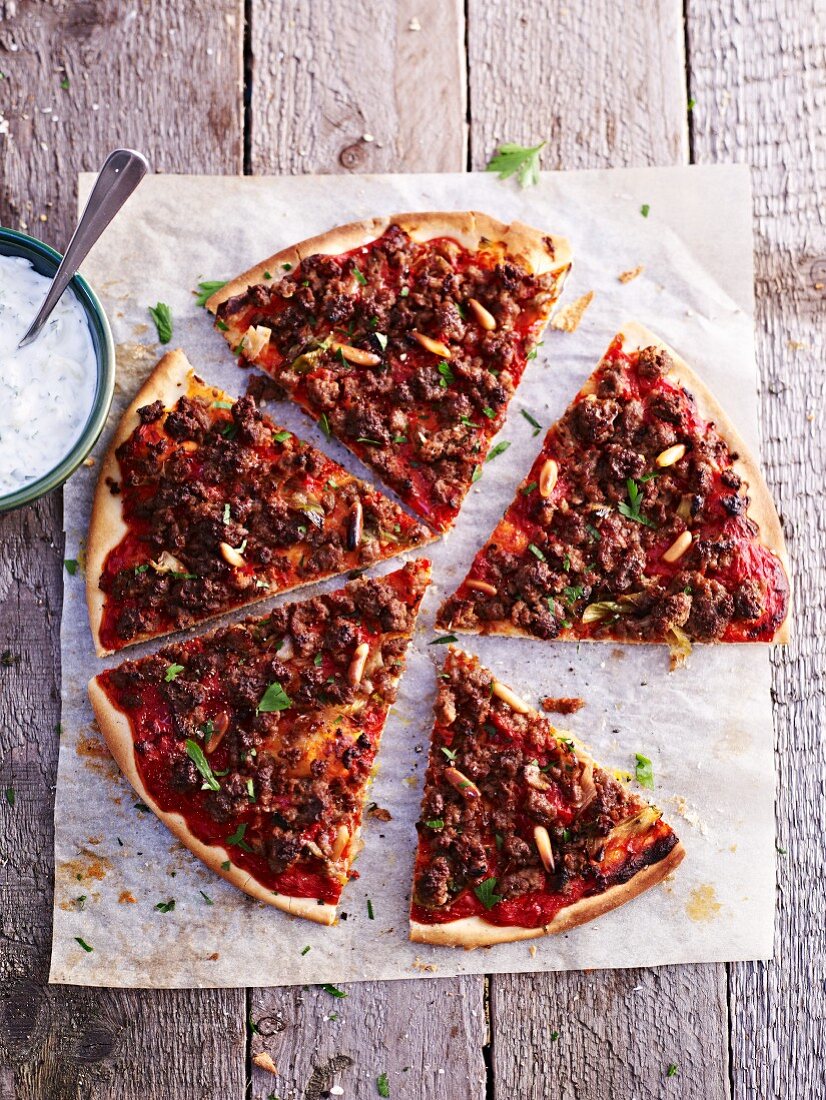 A minced lamb pizza served with a yogurt dip