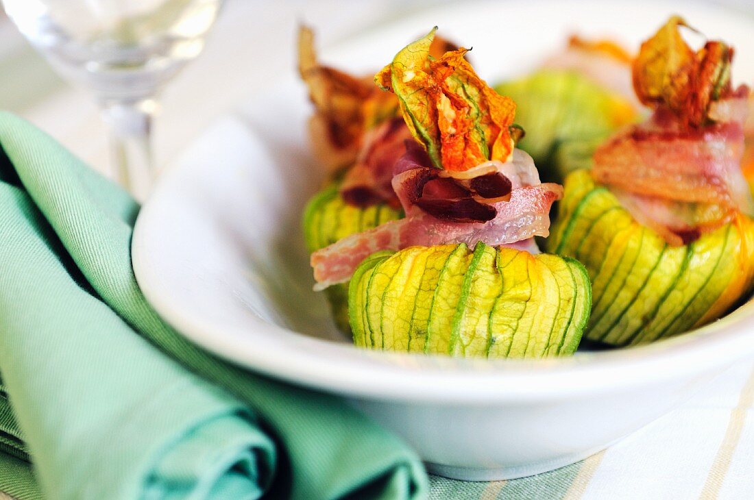 Gefüllte Zucchiniblüten mit Speckstreifen zugebunden