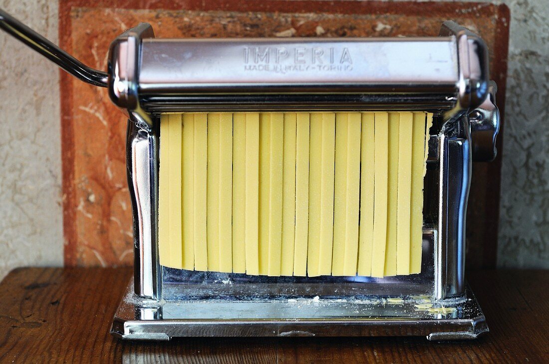 Fresh tagliatelle in a pasta machine