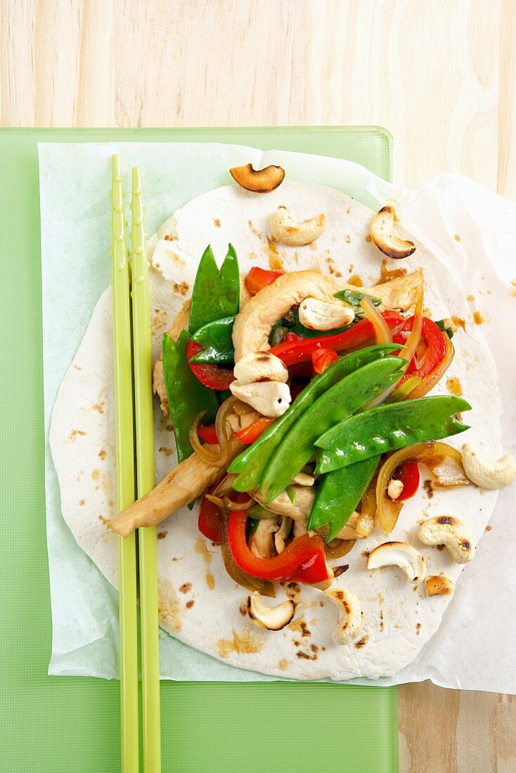 Stir-fried chicken and vegetables with cashew nuts on a wheat tortilla
