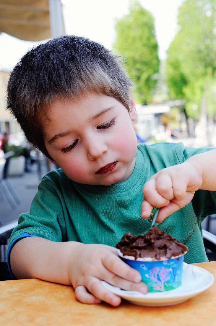 A little boy eating chocolate ice cream in an ice cream cafe
