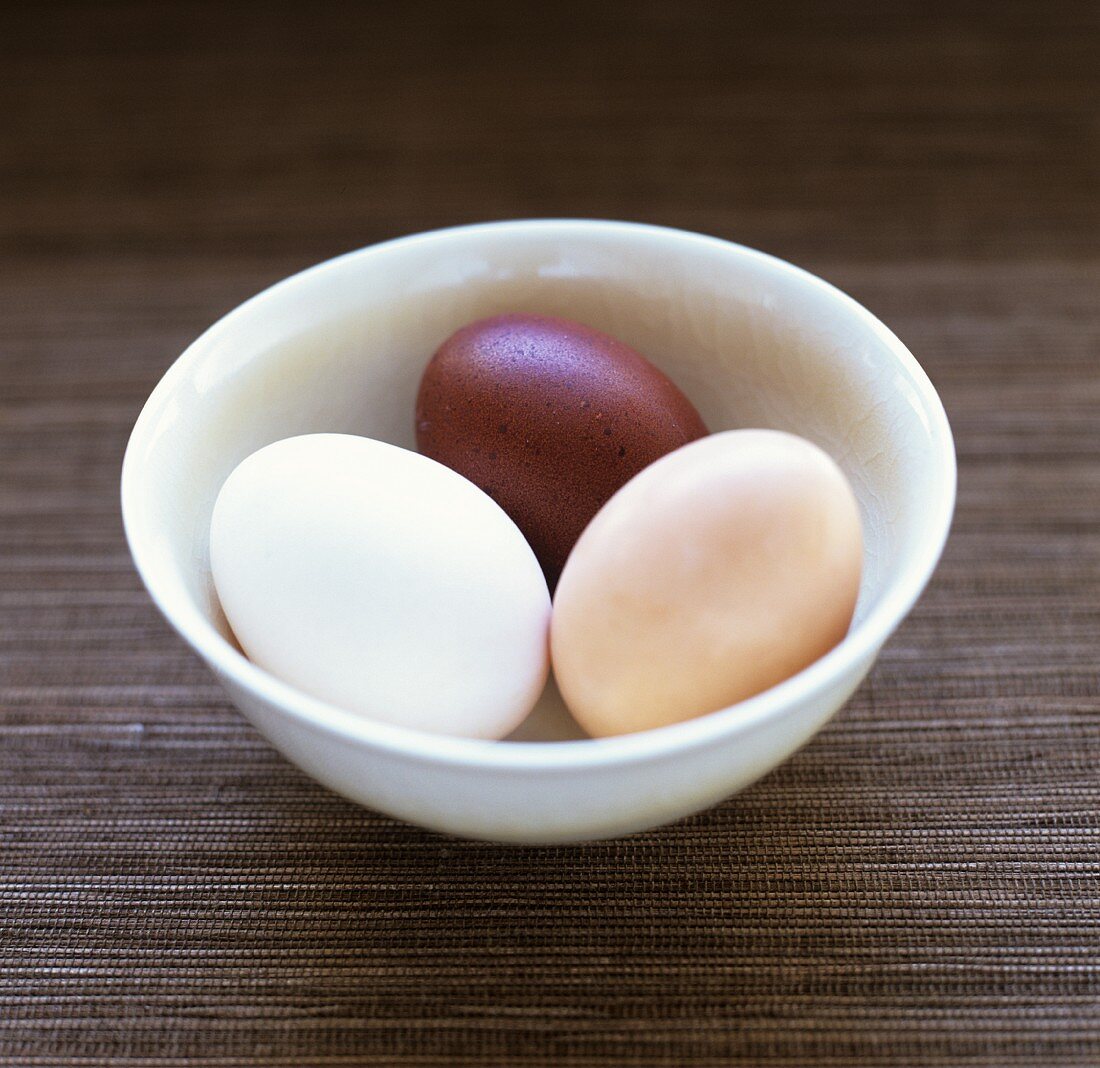 weiße, dunkelbraune und hellbraune Eier in einer Schale