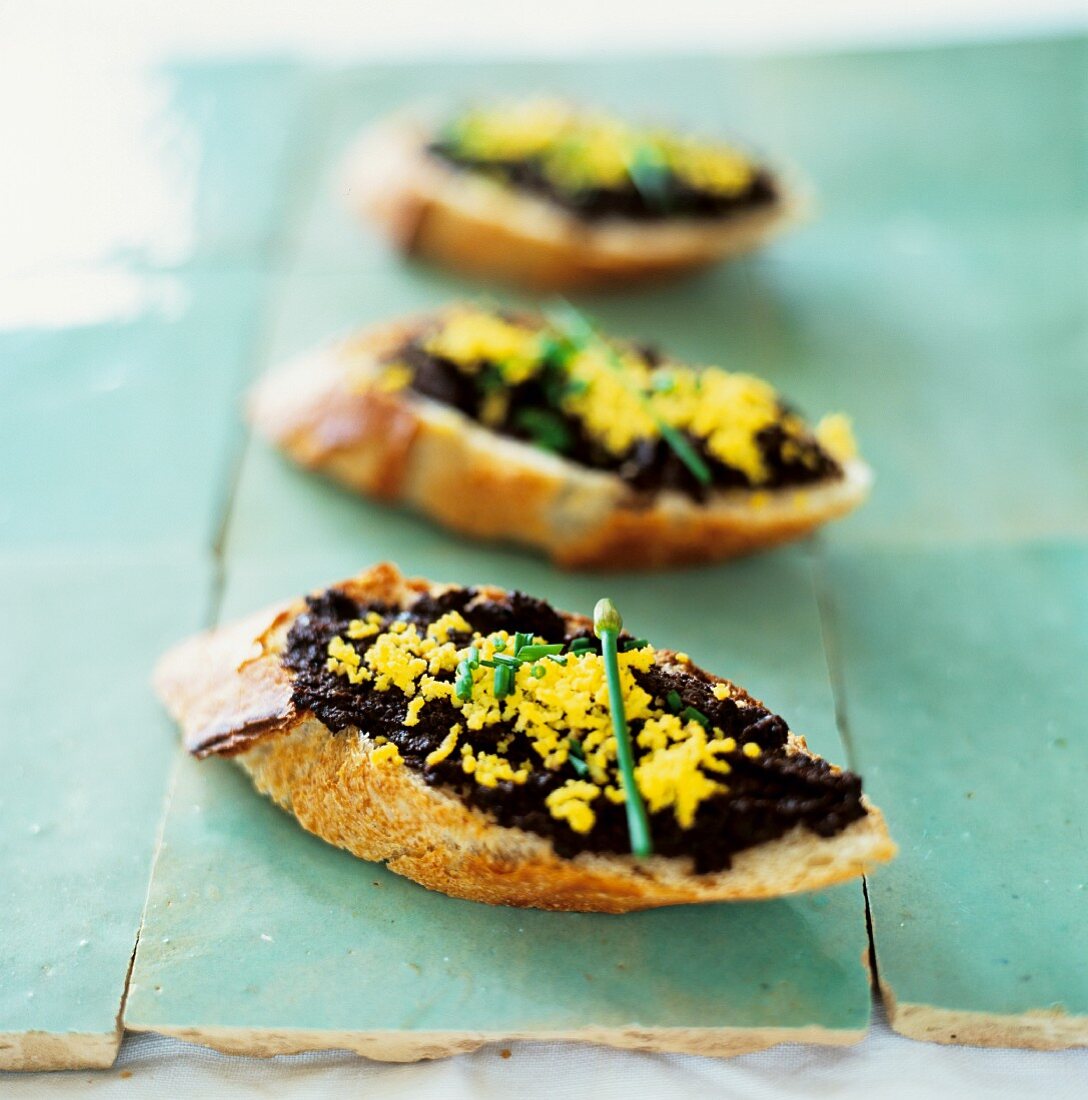 Toasted bread topped with tapenade and egg yolk