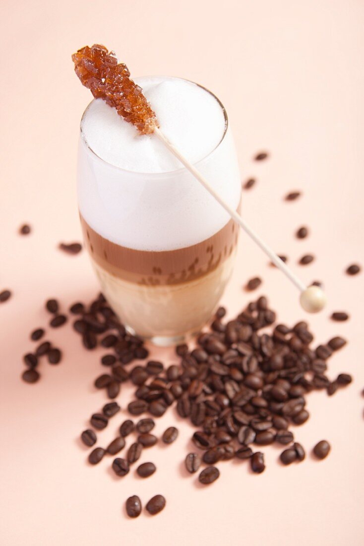 Caffe Latte mit Kandisstick und Kaffeebohnen