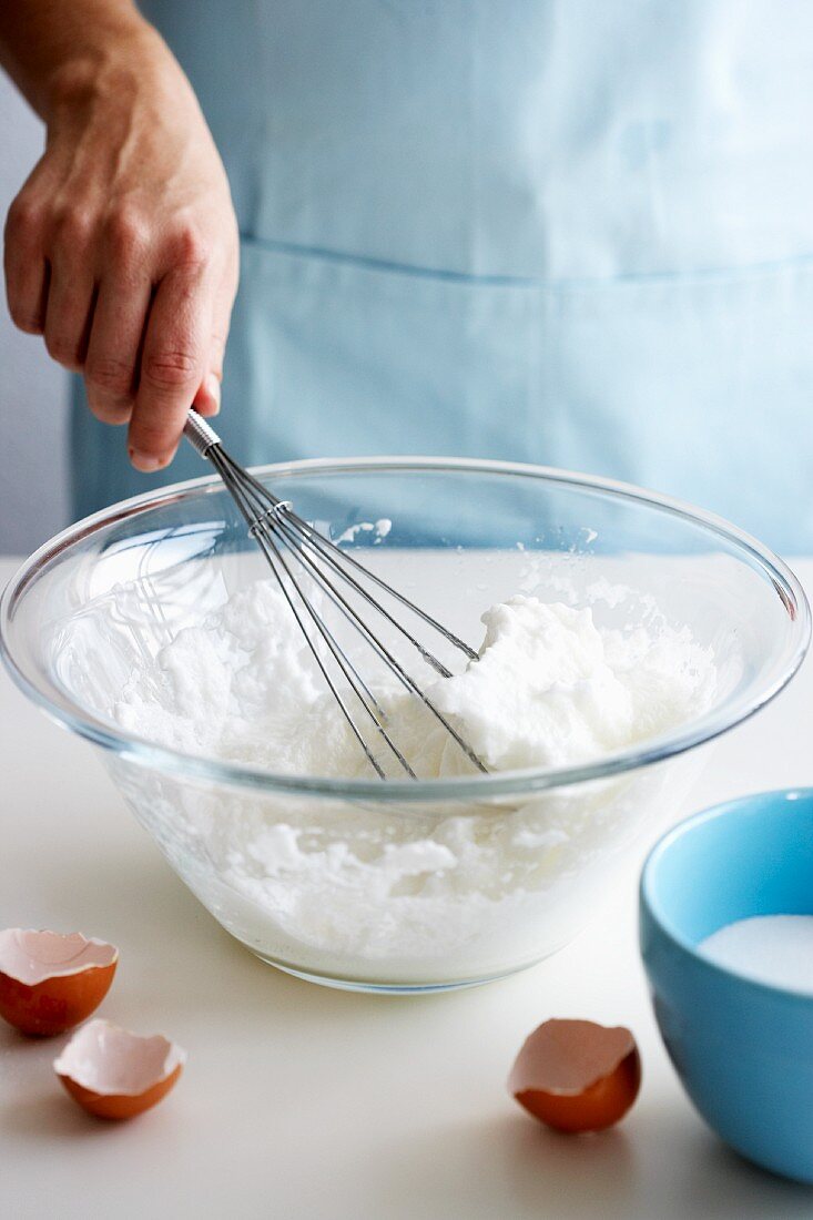 Beaten egg white in a bowl with a whisk