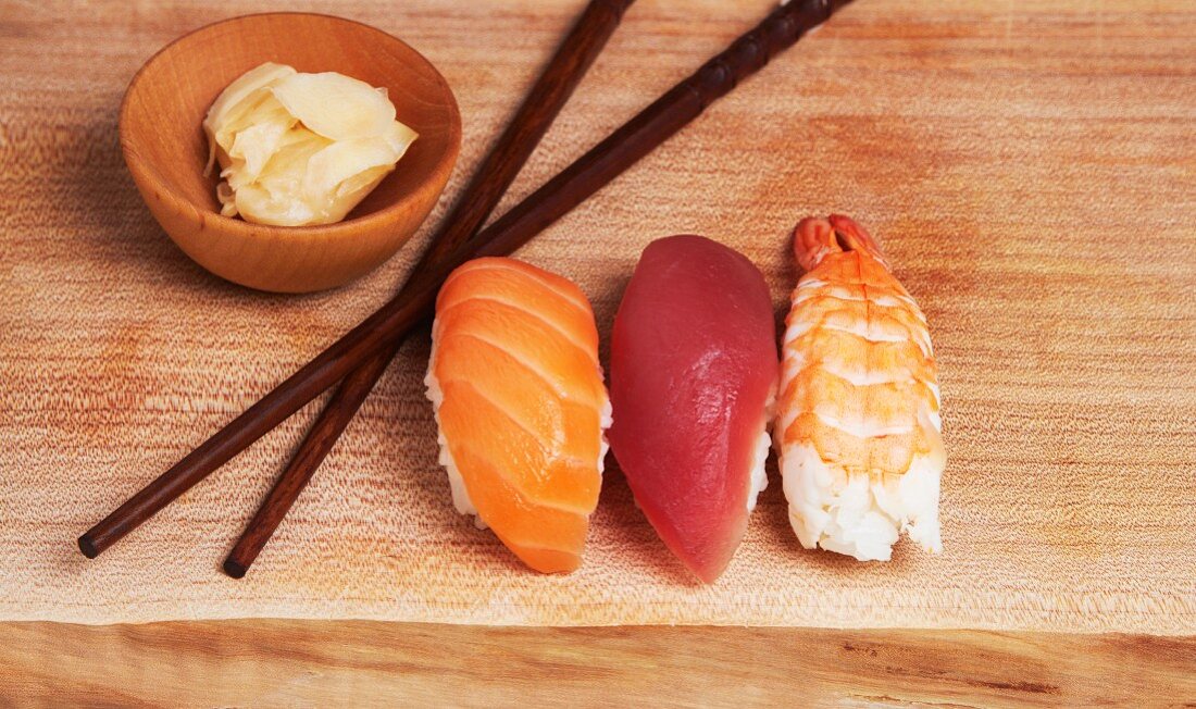 Sashimi Sushi (Salmon, Tuna, Shrimp) on Wood Board with Ginger and Chopsticks