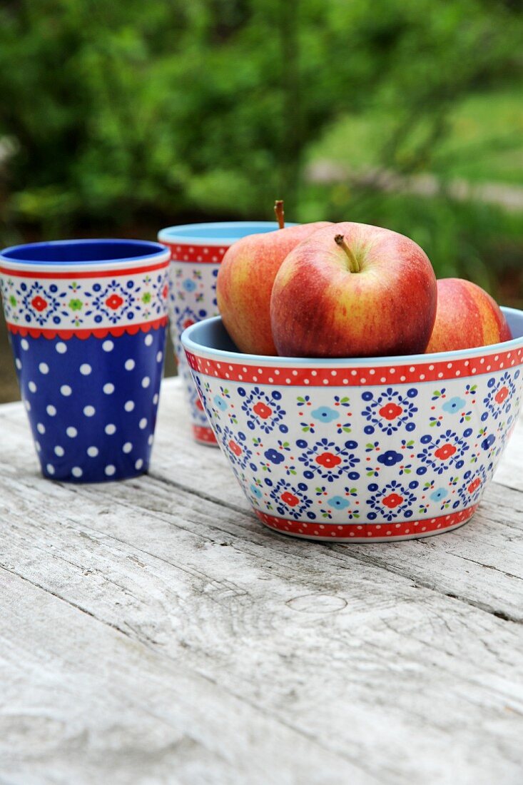 Apples in a colourful bowl on a garden table