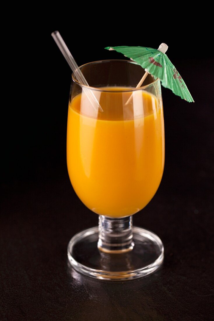 An orange smoothie with a cocktail umbrella