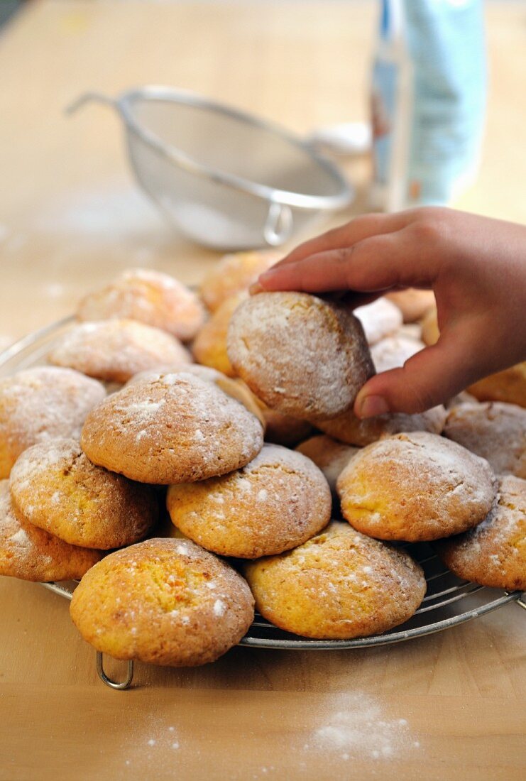 A little boy’s hand taking an Italian pumpkin biscuit