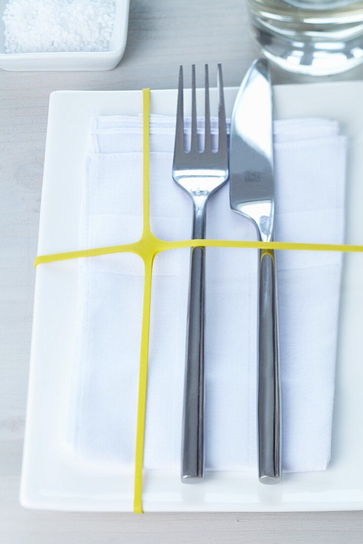White place setting with yellow rubber band across plate